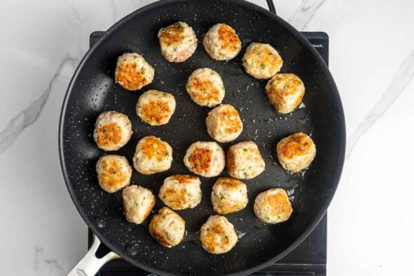 lemon ground chicken meatballs cooking in a nonstick skillet.