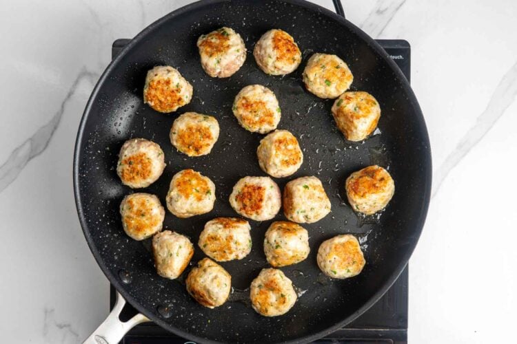 lemon ground chicken meatballs cooking in a nonstick skillet.