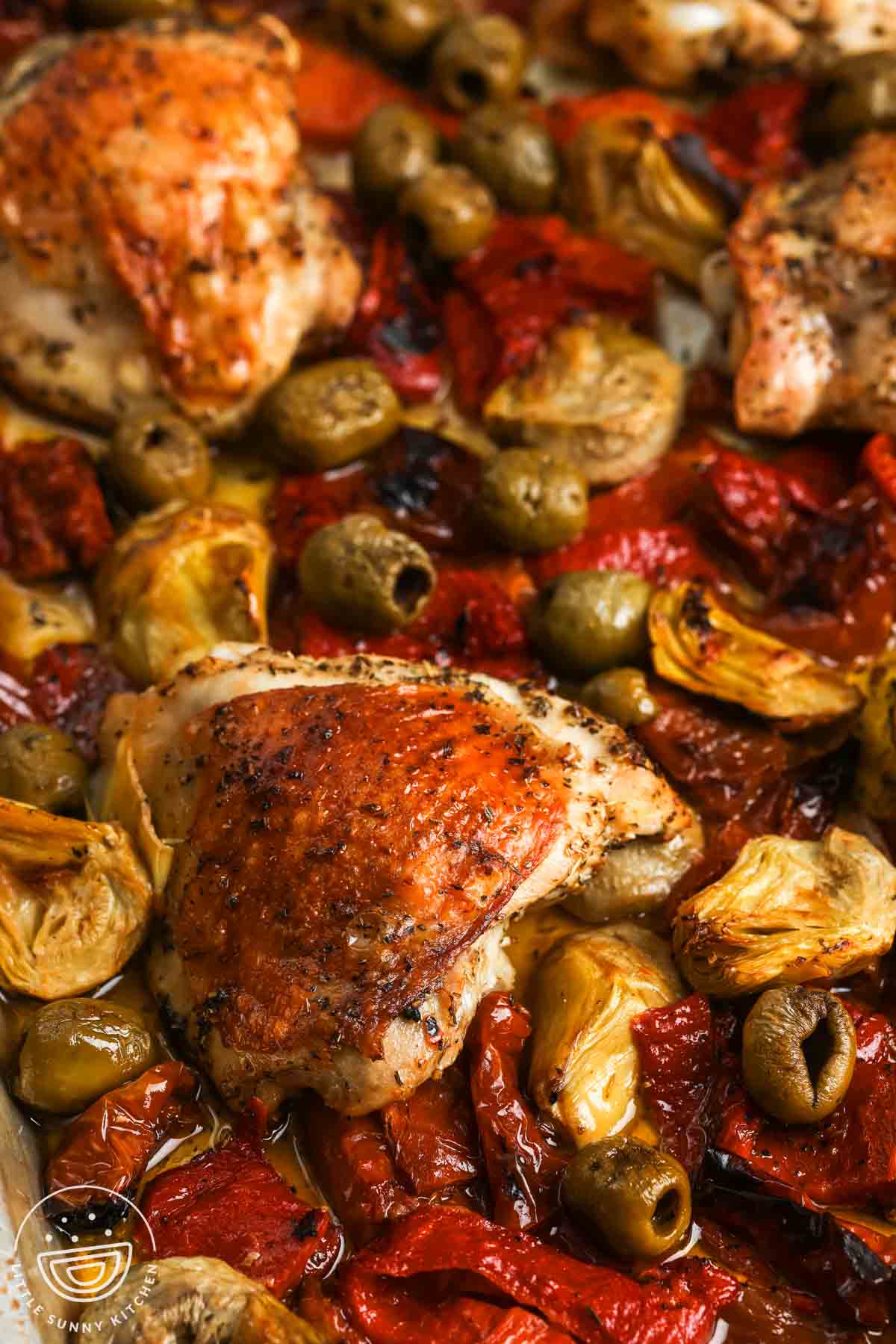 closeup of roasted chicken thighs with olives, sun dried tomatoes.