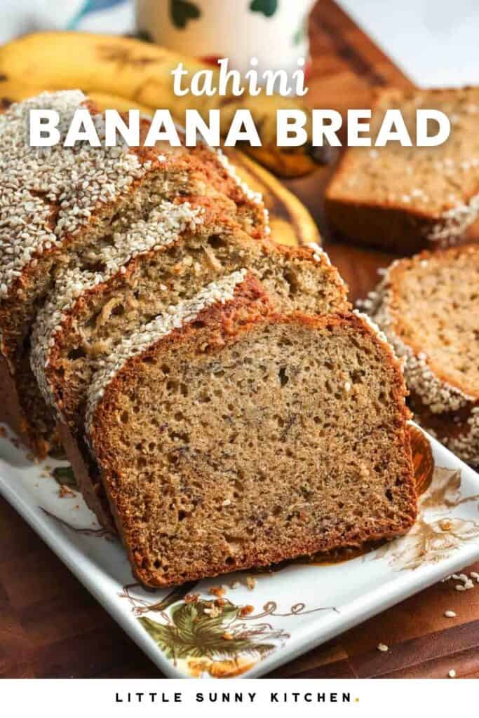 A platter holding a loaf of banana bread that has been sliced. The bread is topped with sesame seeds. Text overlay says "tahini Banana Bread"