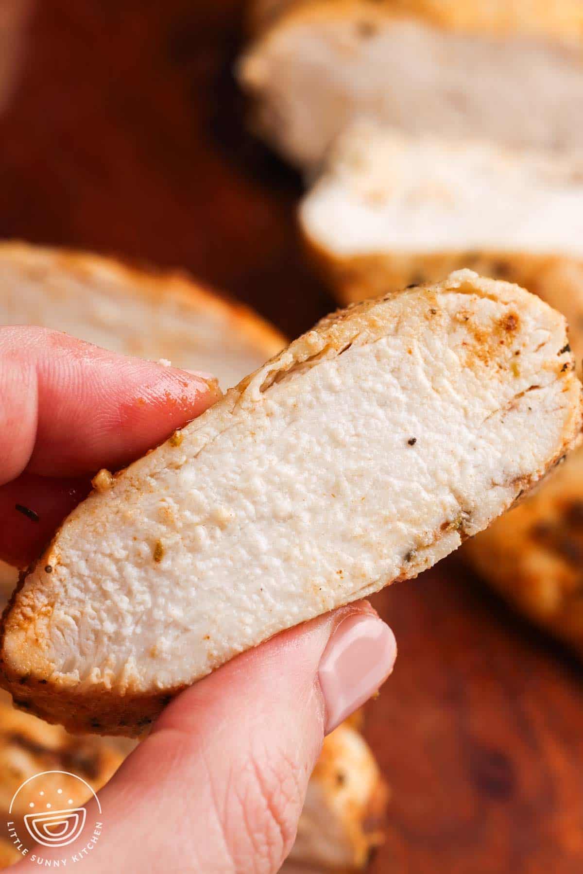 Juicy oven baked chicken breast slice showing the moist interior and seasoned golden crust