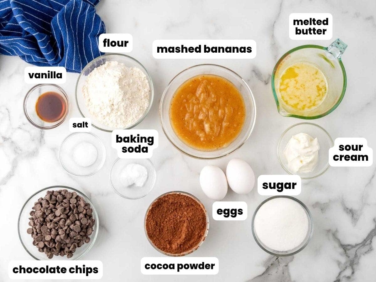 The ingredients for making double chocolate banana bread measured into small glass bowls and set on a marble counter.