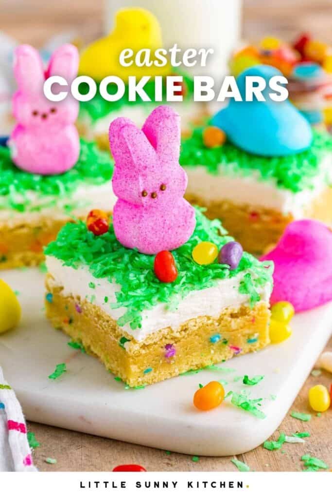 Easter sugar cookie bars topped with coconut frosting, green coconut grass, Peeps marshmallow bunny, and colorful jelly beans.