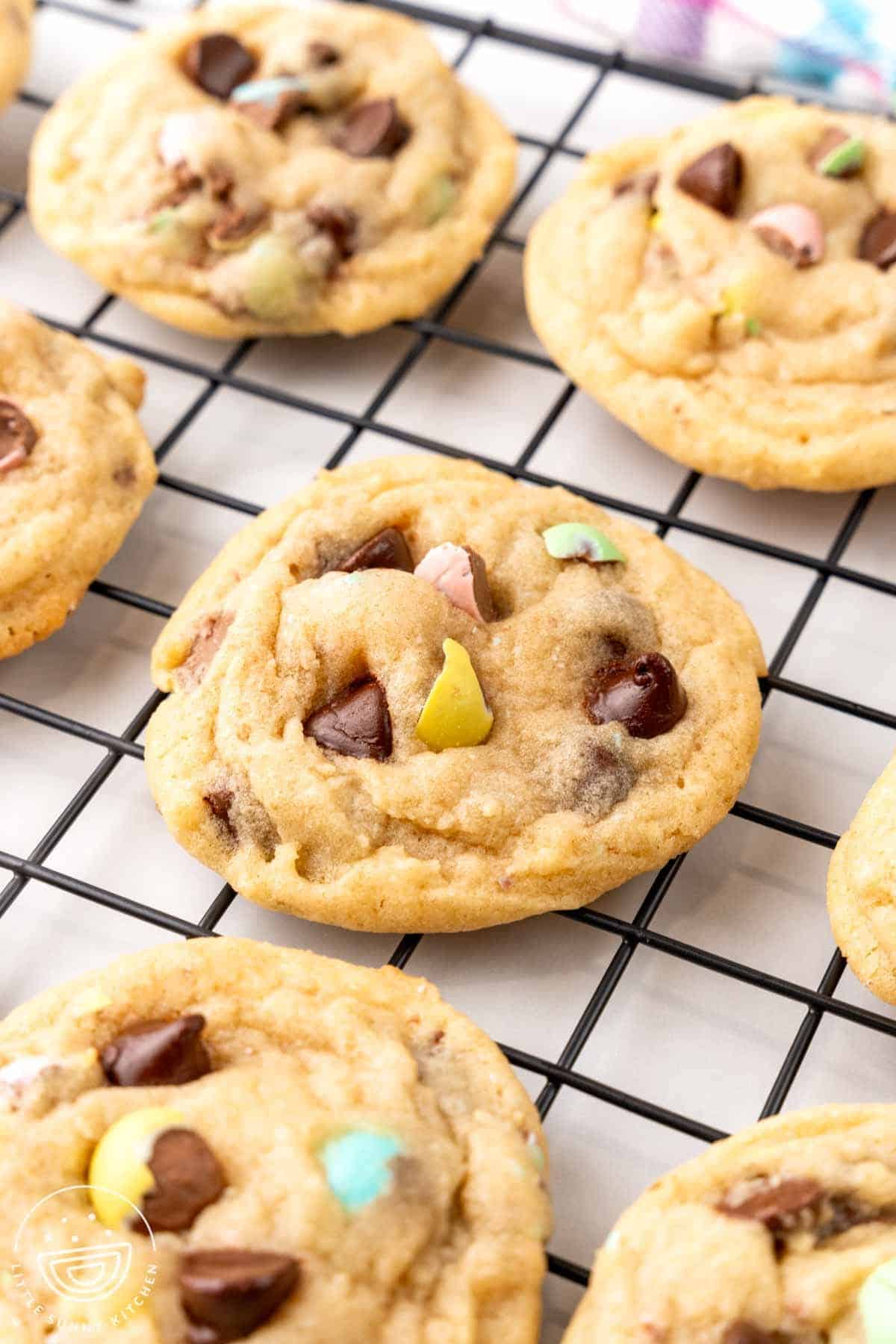 mini egg chocolate chip cookies cooling on a black wire rack.