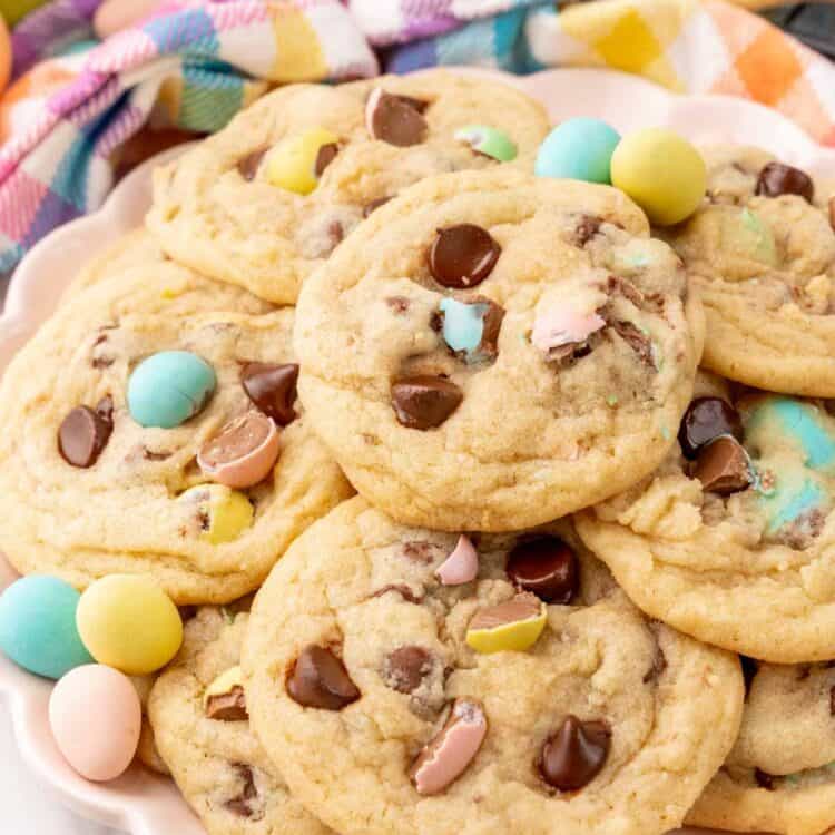 a pink scalloped plate of cadbury mini egg cookies, decorated with extra candy eggs.