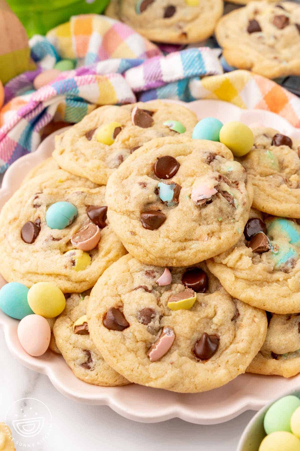 a pink scalloped plate of cadbury mini egg cookies, decorated with extra candy eggs.