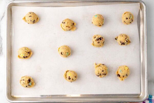 cookie dough balls on a parchment paper lined cookie sheet.
