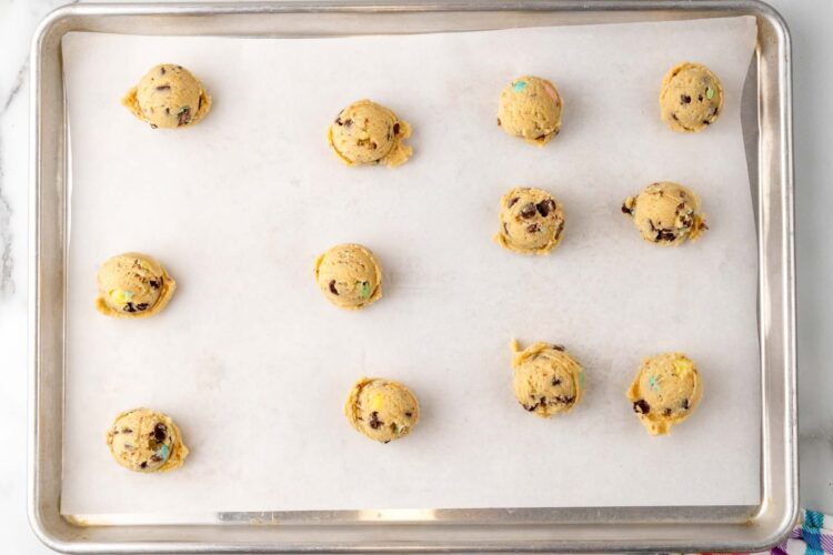 cookie dough balls on a parchment paper lined cookie sheet.