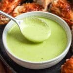 Peruvian green sauce (aji verde) in a bowl with roasted chicken