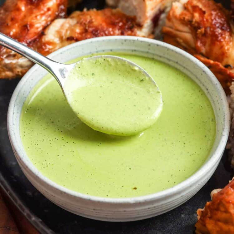 Peruvian green sauce (aji verde) in a bowl with roasted chicken
