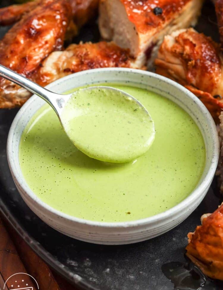Peruvian green sauce (aji verde) in a bowl with roasted chicken