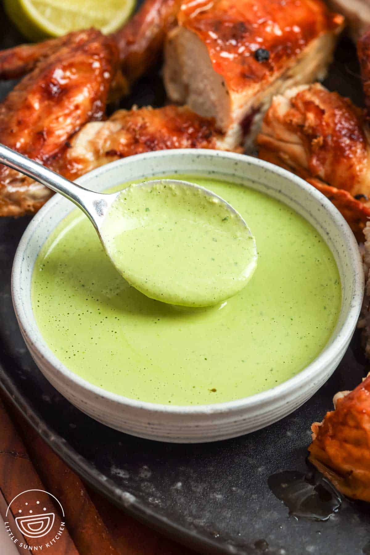 Peruvian green sauce (aji verde) in a bowl with roasted chicken