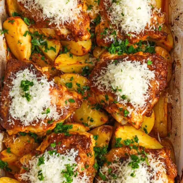 overhead view of a 9x13 baking dish of cooked potato wedges topped with bone in chicken thighs. each piece of chicken is topped with grated parmesan cheese.