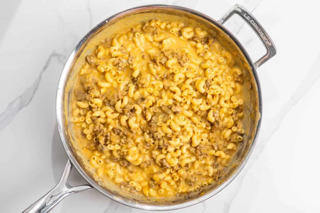 creamy cheesy mac and cheese with ground beef in a skillet.