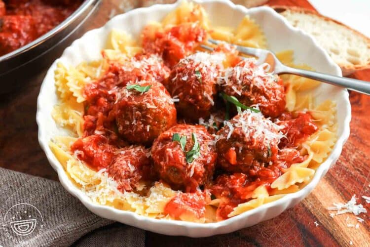 a bowl of meatballs and sauce served over farfalle pasta.