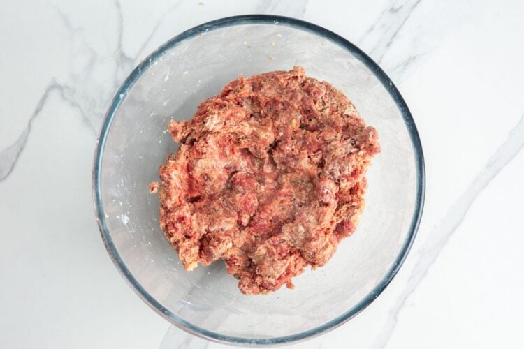 meat mixture for ricotta meatballs, gently combined in a glass mixing bowl.