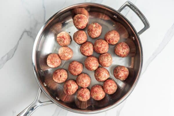 ricotta meatballs browning in a metal skillet.