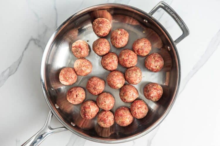ricotta meatballs browning in a metal skillet.
