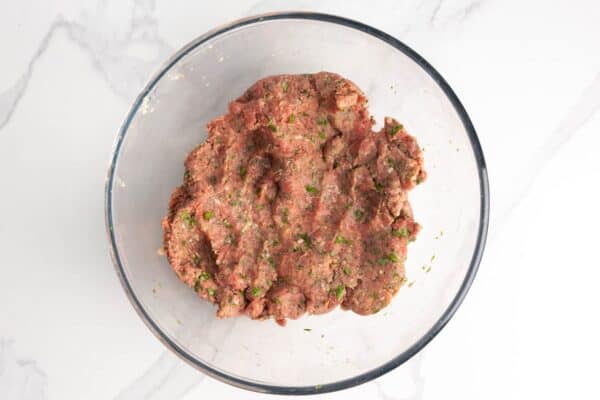 meat mixture for Greek meatballs in a glass mixing bowl.
