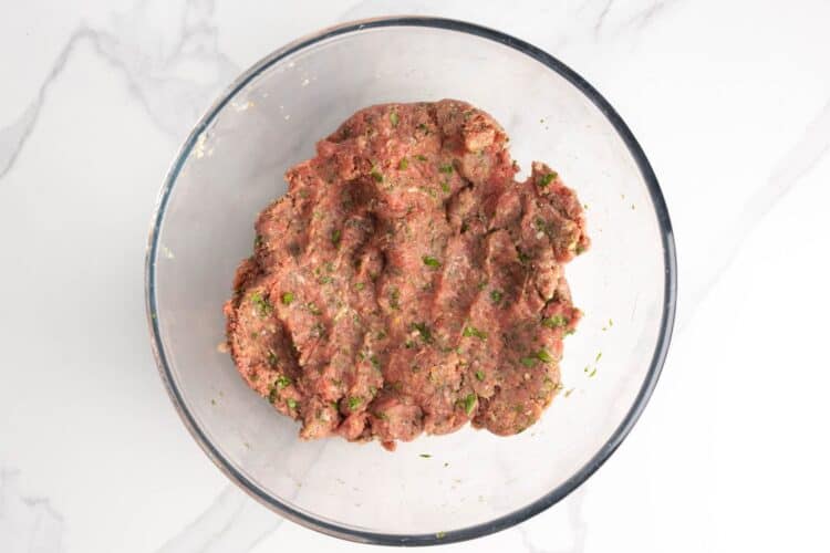 meat mixture for Greek meatballs in a glass mixing bowl.