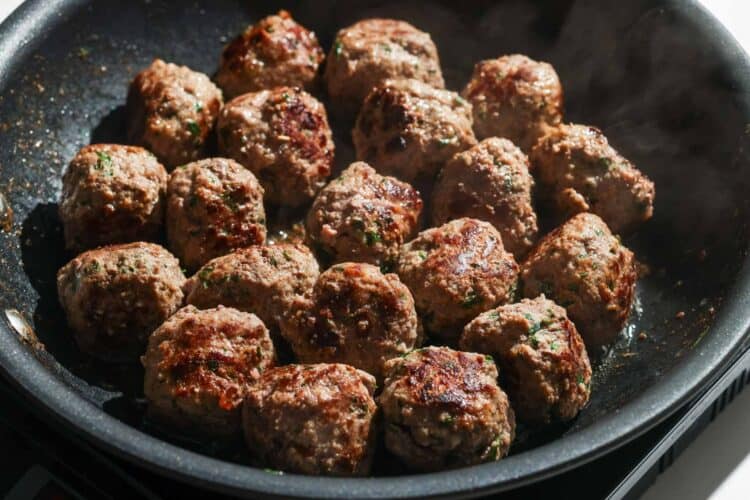 Greek meatballs cooked in a skillet until they're browned on all sides.