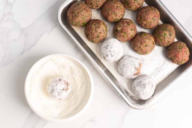Raw greek meatballs rolled in all purpose flour before cooking.