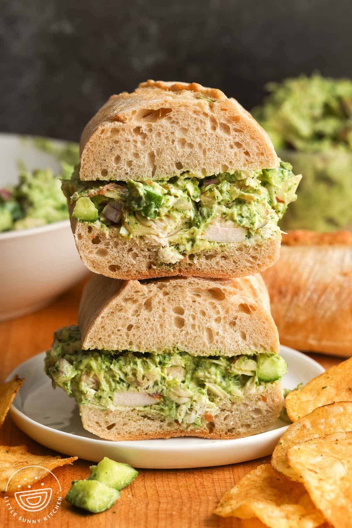 Green goddess chicken salad sandwich on crusty bread with chips on the side.