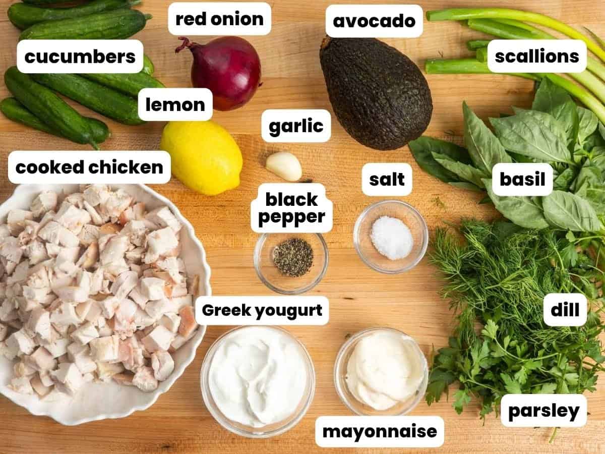 Ingredients for green goddess chicken salad, including cooked chicken, cucumbers, red onion, avocado, scallions, lemon, garlic, Greek yogurt, mayonnaise, basil, dill, parsley, salt, and black pepper.