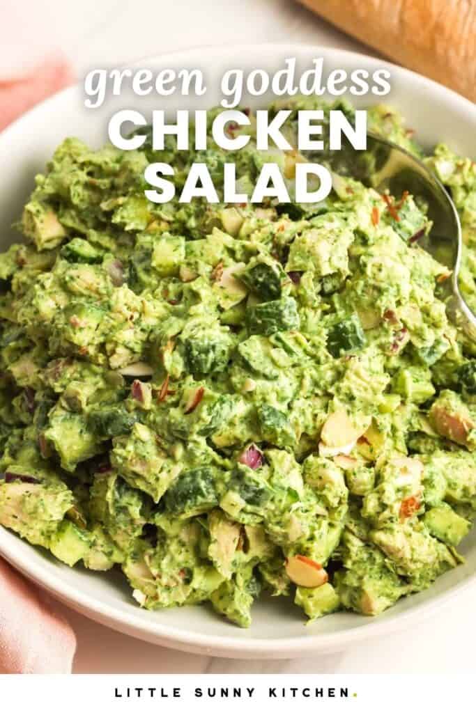 Green goddess chicken salad in a white bowl with diced cucumber, red onion, herbs, creamy avocado dressing, and sliced almonds.
