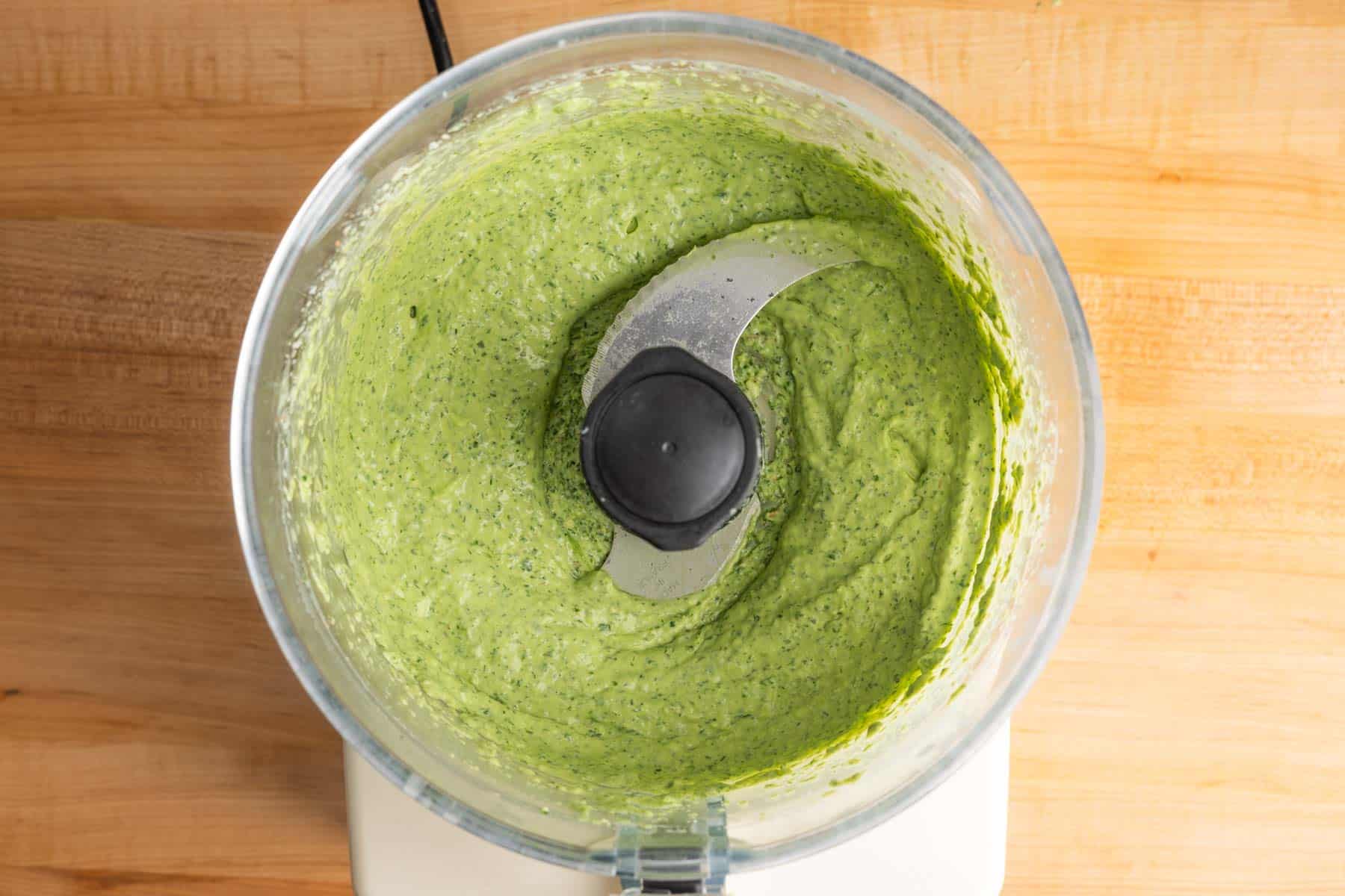 Creamy green goddess dressing blended in a food processor.