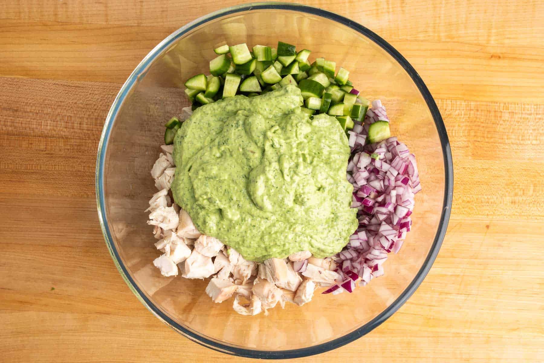Green goddess dressing poured over chopped chicken, cucumber, red onion, and scallions.