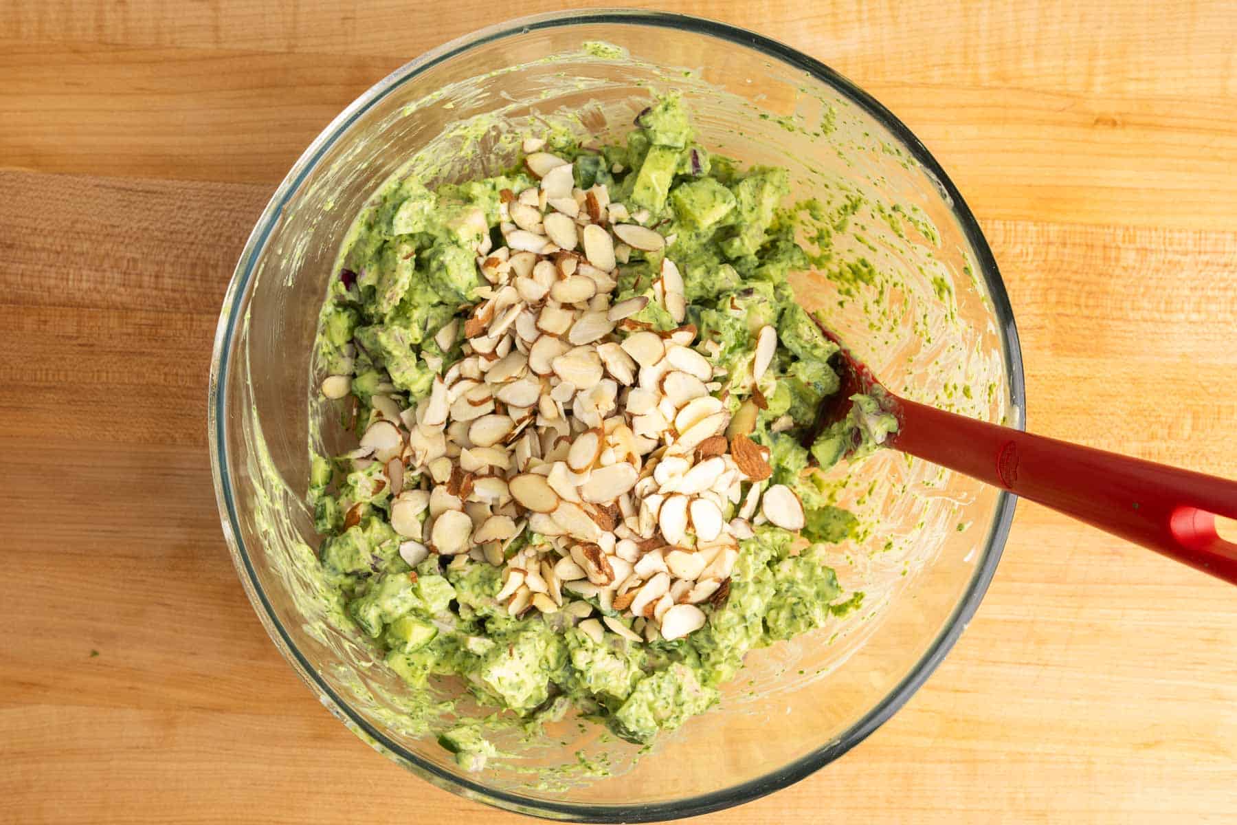 Green goddess chicken salad mixed in a bowl with sliced almonds on top.