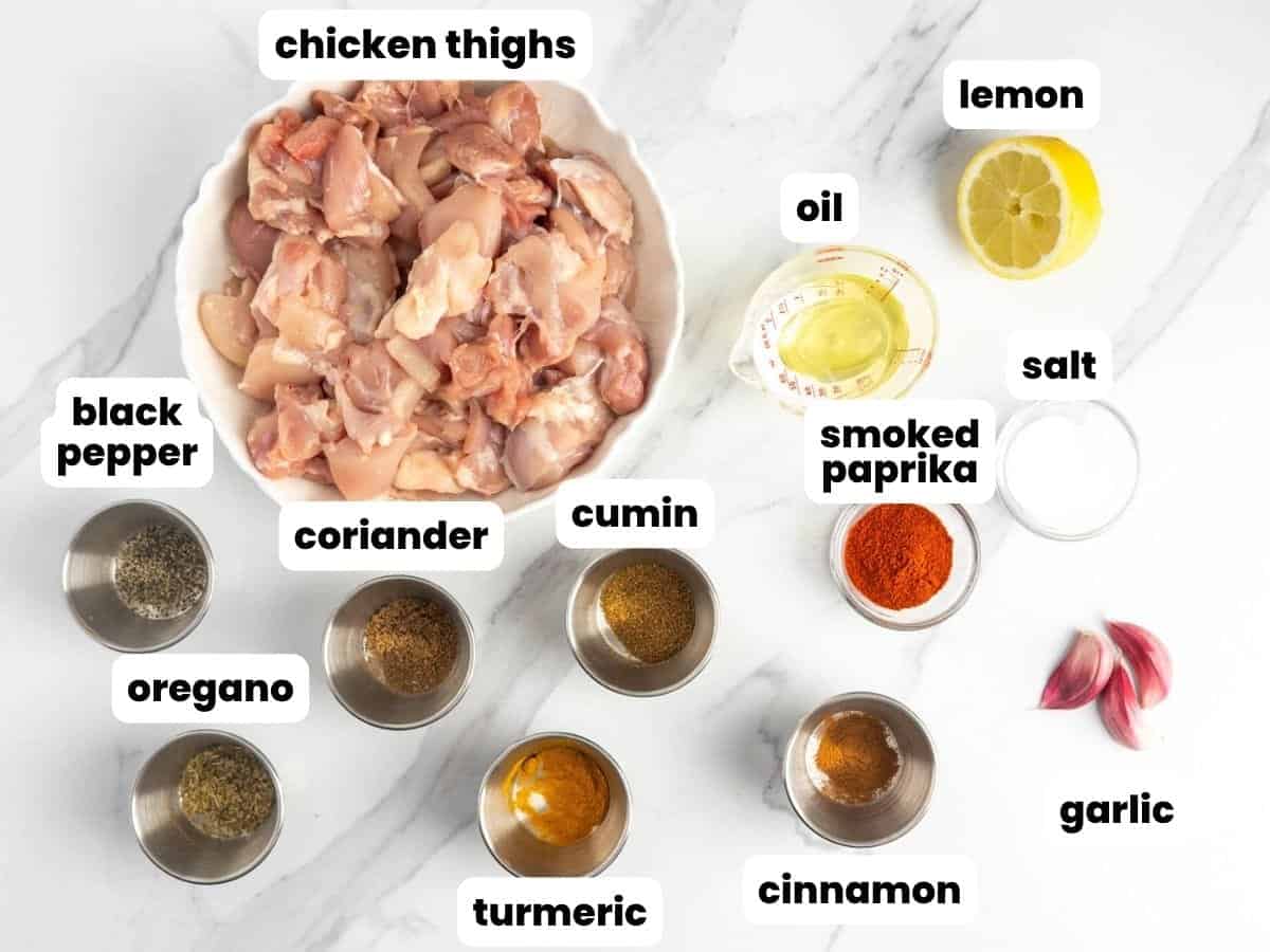 A bowl of chopped chicken thighs with seasonings needed to make halal cart chicken all in small bowls.