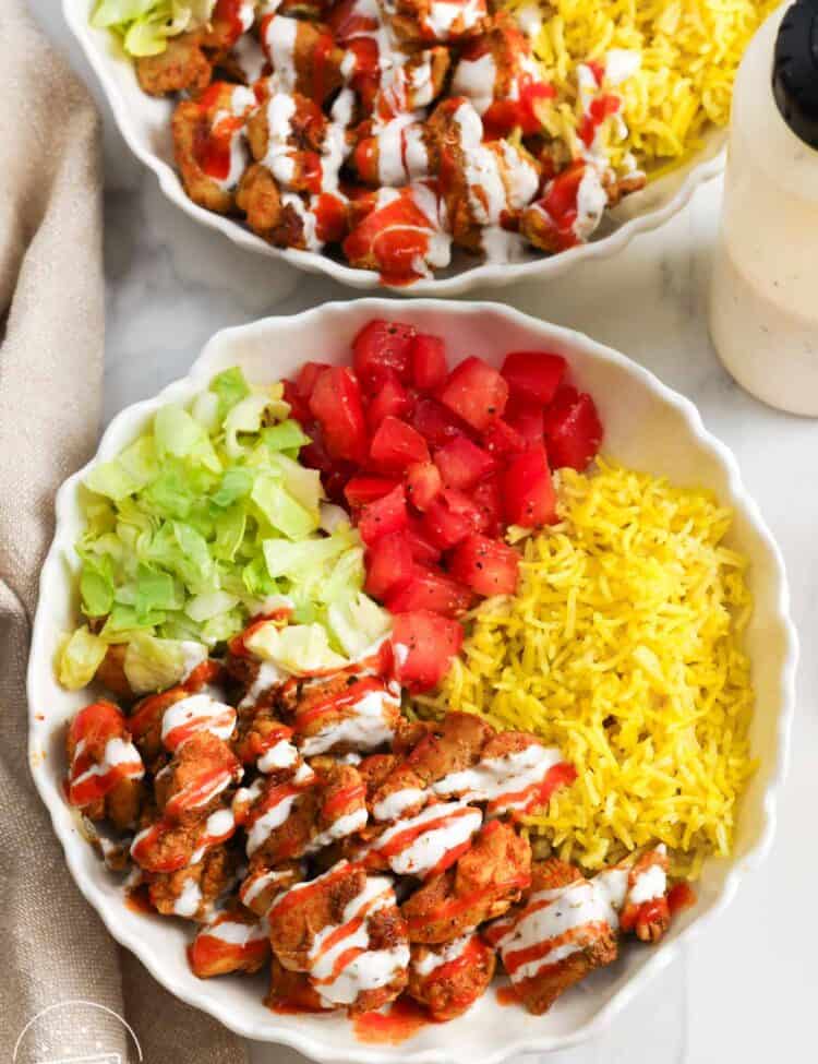 overhead view of two homemade halal cart rice bowls with chicken.