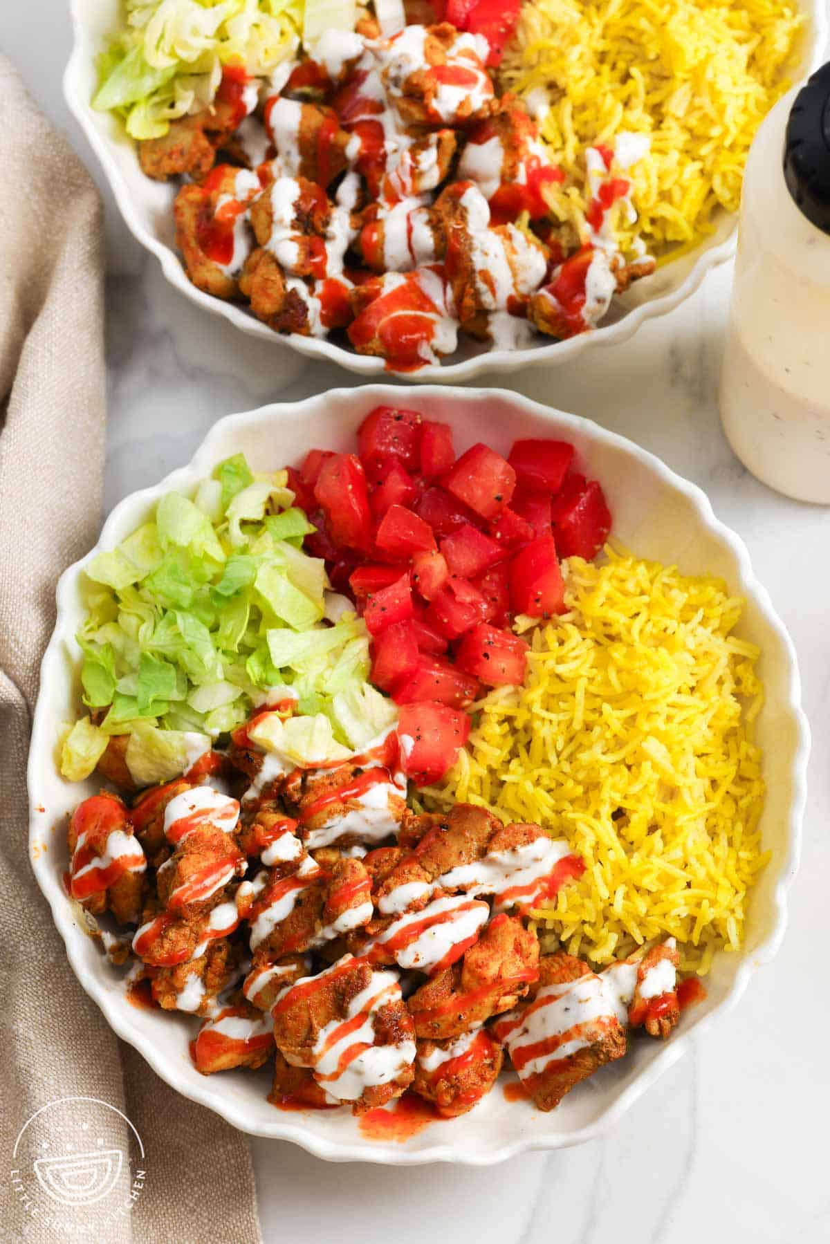 overhead view of two homemade halal cart rice bowls with chicken.