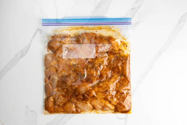 diced raw chicken thighs marinating in a plastic bag.