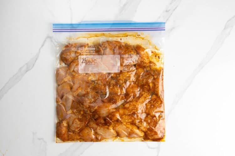 diced raw chicken thighs marinating in a plastic bag.