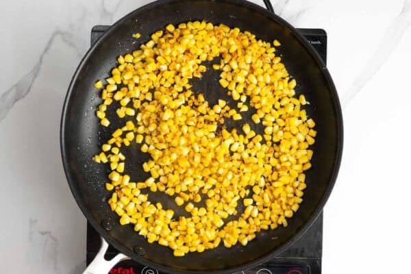 fresh corn kernels charred in a pan.