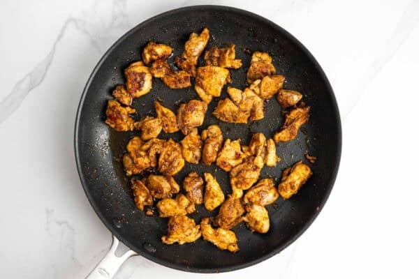 seasoned diced chicken thighs seared in a non-stick skillet.