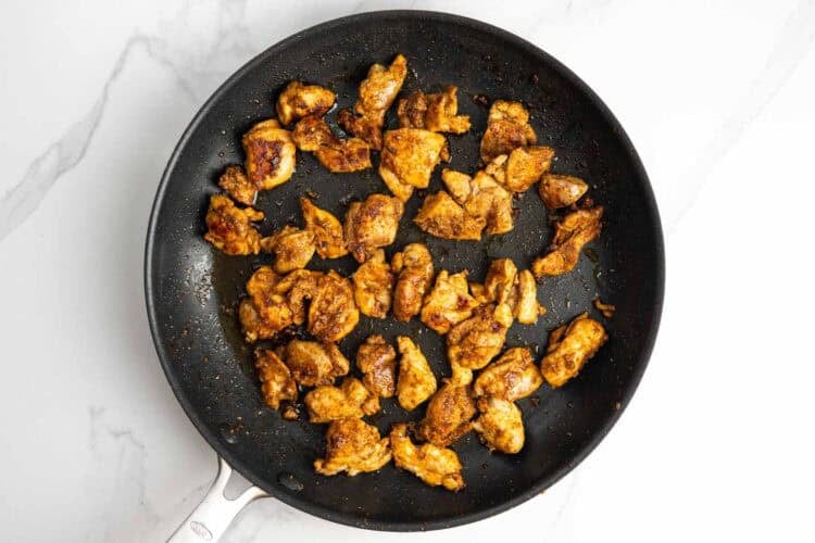 seasoned diced chicken thighs seared in a non-stick skillet.