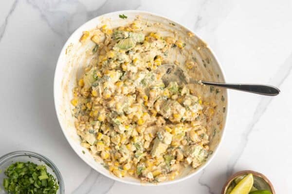creamy salad made with charred corn, avocado, and seasonings, in a large bowl.