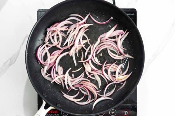 sliced red onion sauteed in a skillet.