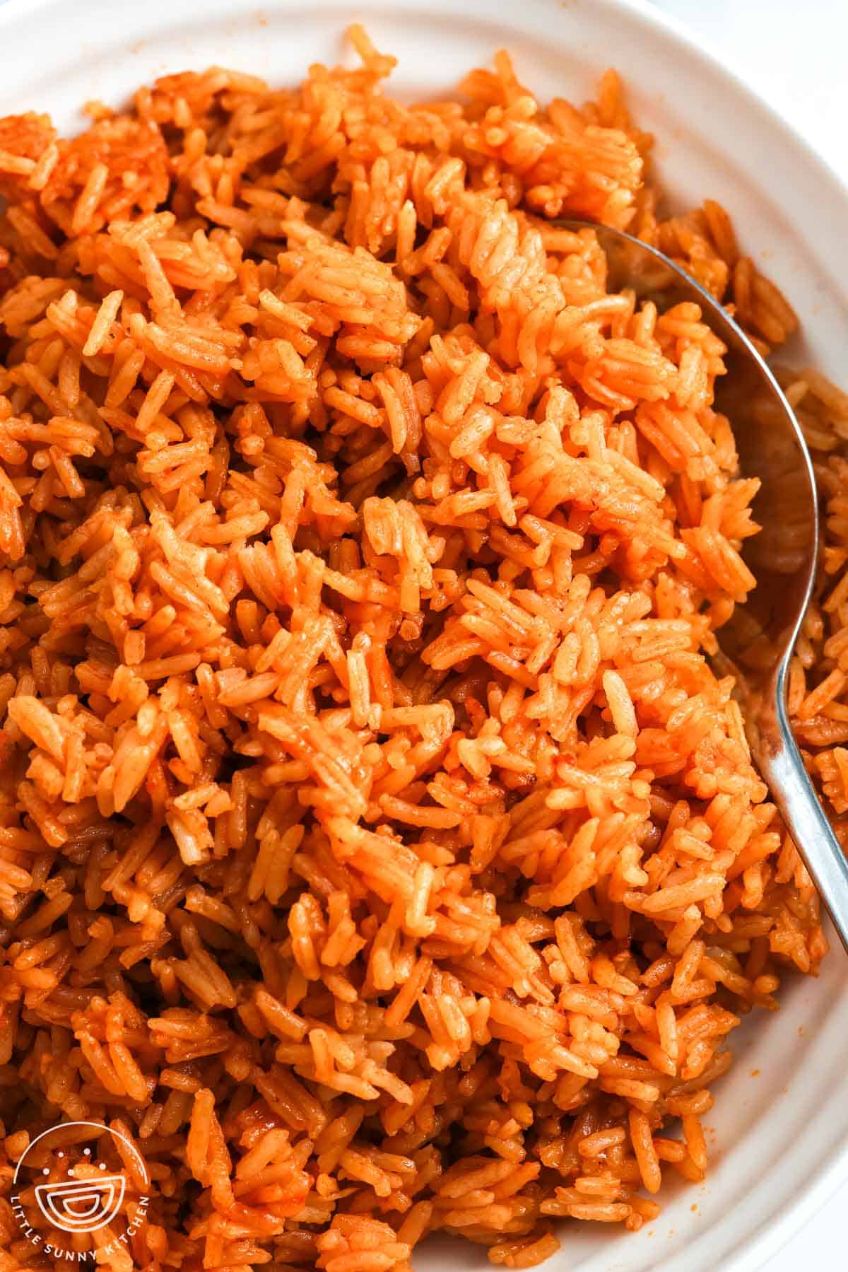 Close-up of red-orange Vietnamese tomato rice with fluffy jasmine rice grains and a spoon.