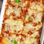 baked zucchini lasagna, cut into 8 squares and garnished with basil leaves.