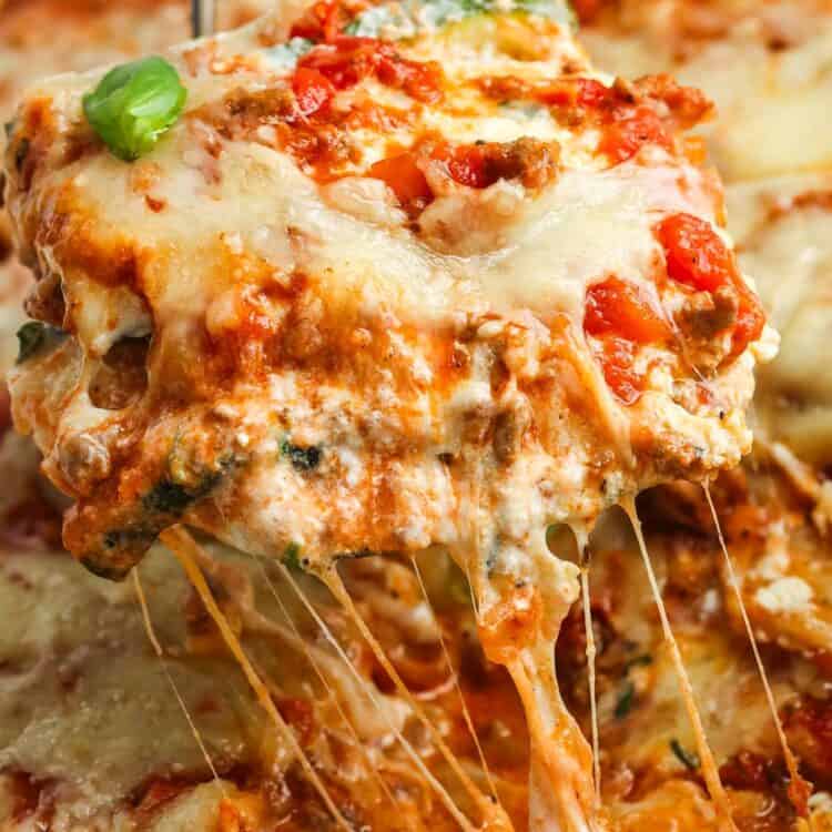 a slice of zucchini lasagna lifted up, showing melty cheese and a creamy texture.