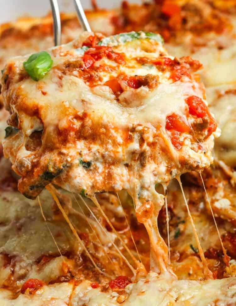a slice of zucchini lasagna lifted up, showing melty cheese and a creamy texture.