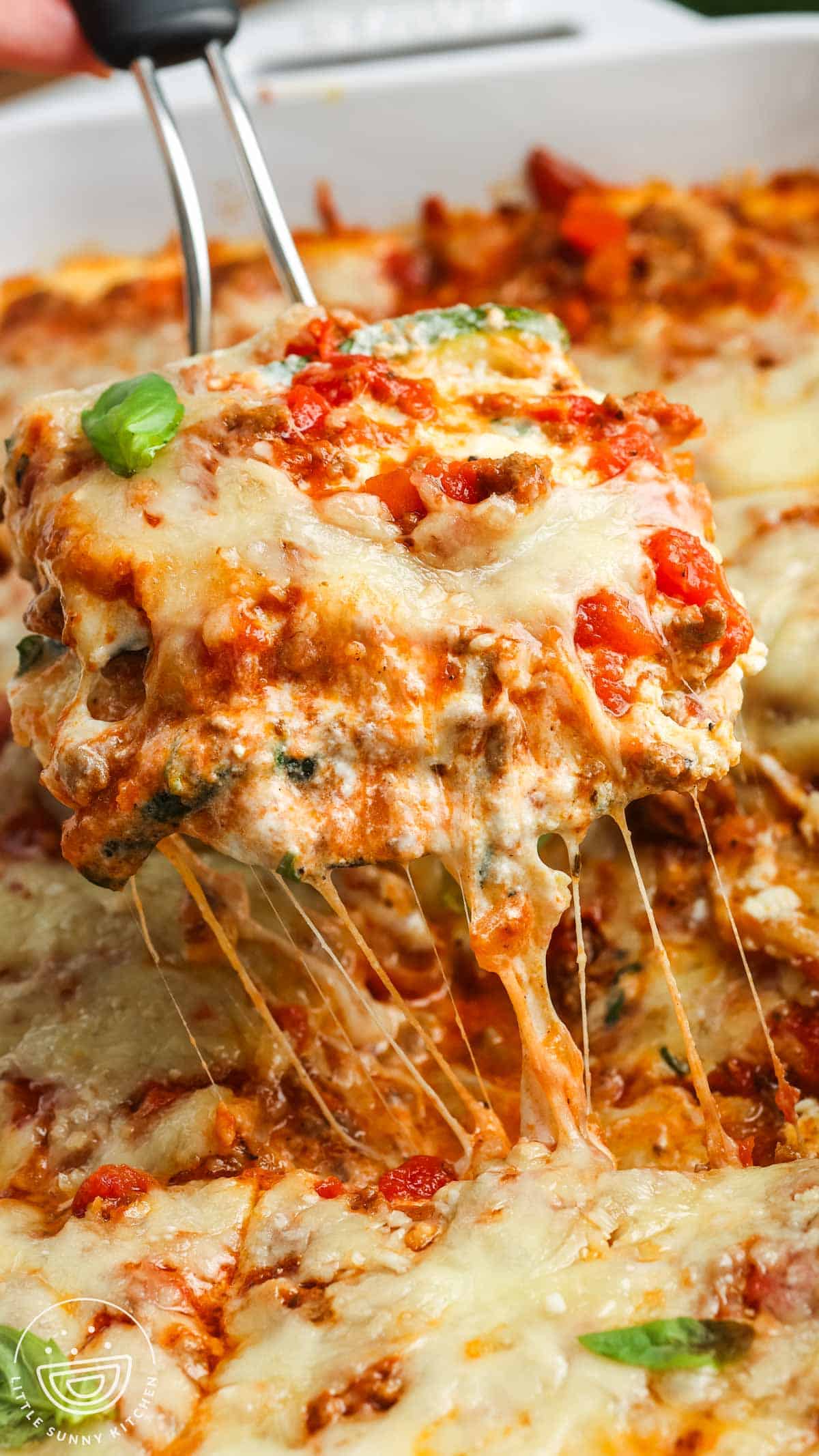 a slice of zucchini lasagna lifted up, showing melty cheese and a creamy texture.