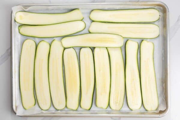 slices of zucchini arranged on a parchment lined baking sheet.