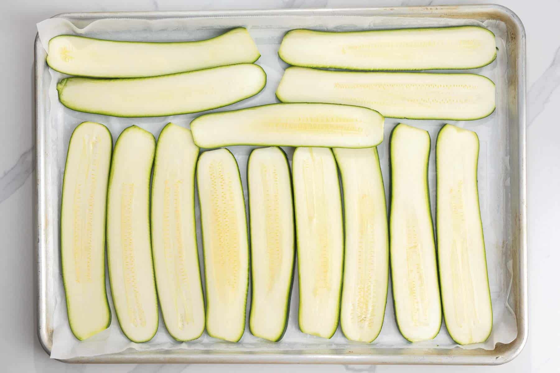 slices of zucchini arranged on a parchment lined baking sheet.