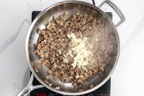 ground beef cooked with garlic and onions in a skillet.